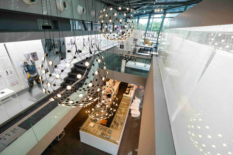 Wide-angle view of the museum gallery showing prototypes and information panels upstairs, with the design museum shop downstairs