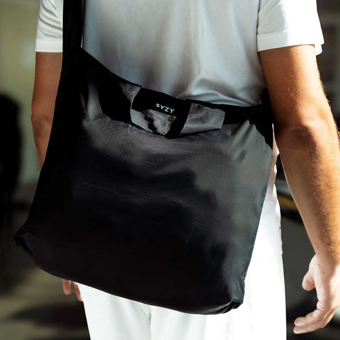 Close up view of a model with a black tetra tote bag in a crossbody form