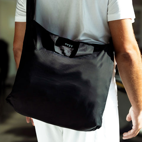 Close up view of a model with a black tetra tote bag in a crossbody form