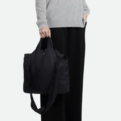 Model hand carrying a black tetra tote bag