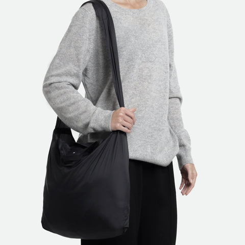 Model using the black tetra tote bag in a on shoulder form