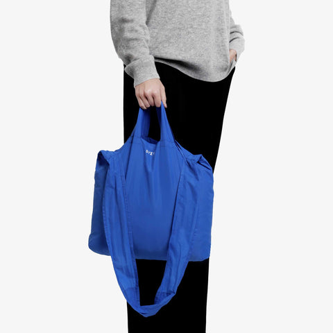 Model hand carrying a blue cobalt tetra tote bag