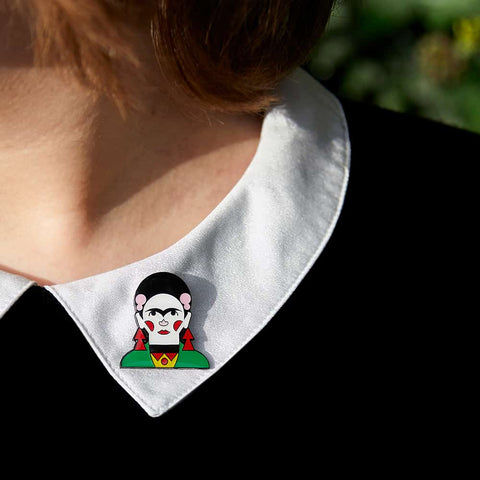 A model proudly wears a enamel pin from Chatty Feet featuring Frida