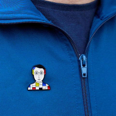 A model proudly wears a enamel pin from Chatty Feet featuring Piet Mondrian