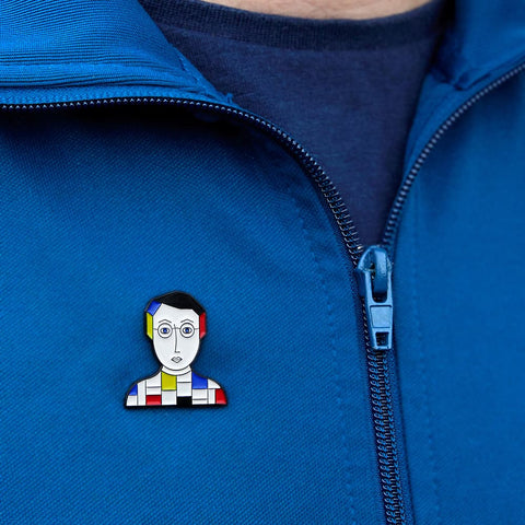 A model proudly wears a enamel pin from Chatty Feet featuring Piet Mondrian