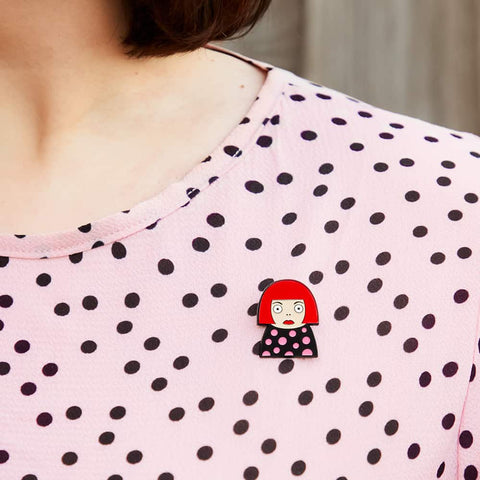 A model proudly wears a enamel pin from Chatty Feet featuring Yayoi Kusama