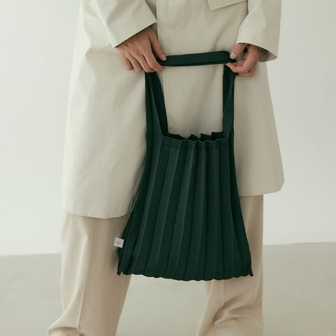 Model in a chic suit gently holds the Pleatsmama Shoulder Bag Solid, showcasing its elegant pleats and effortless everyday style