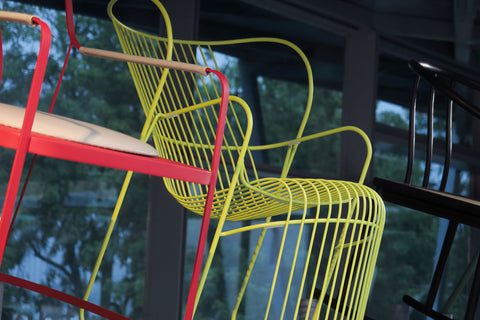 Award winning yellow and red metal frame chairs on display against a blurred Marina bay background