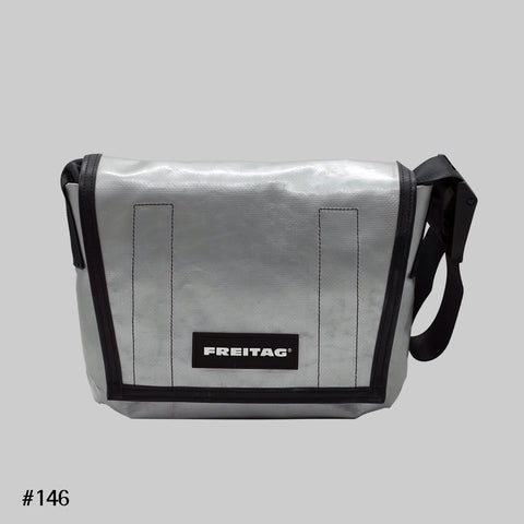 Front view of FREITAG F11 LASSIE messenger bag in silver, with a light blue stripe and black strap