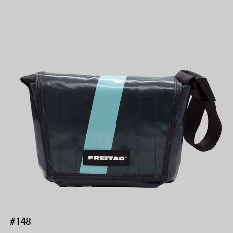 Front view of FREITAG F11 LASSIE messenger bag in grey and blue, with a light blue stripe and black strap