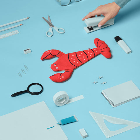 Don Fisher Lobster case with a sea of scissors, notepad, pencils, glasses, tape, stapler, small items which can be fit into the case