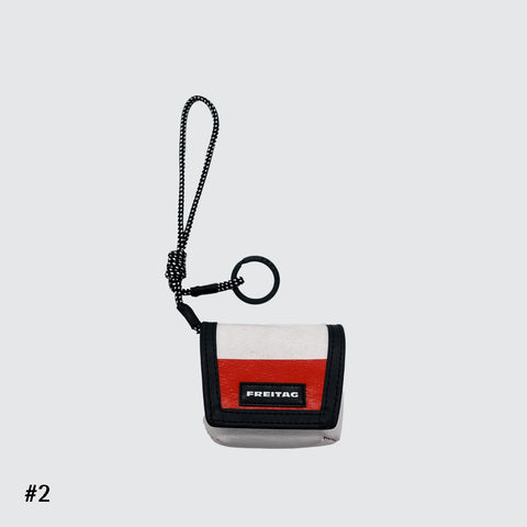 Front view of FREITAG F213 Mini Messenger key holder in offwhite and red with nylon cord.