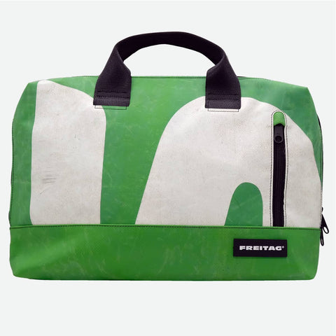 FREITAG F301 MOSS front image with a fresh, medium green base anchors the bag, overlaid with large off-white graphic shapes that add bold contrast and visual movement. The look is finished with deep black handles, zipper, and label, giving it a crisp, structured edge against the softer, slightly worn green and white surfaces
