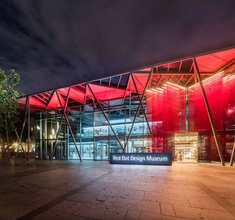 Night view of Red Dot Design Museum – bright red-hue from hanging mesh and light installation
