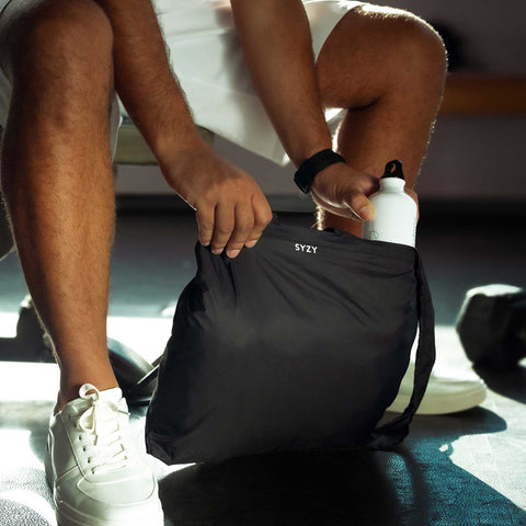 Model showcasing the versatility of Tetra tote bag by having the storage room to place multiple items when expanded