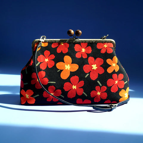 Floral-patterned Clasp Sling Bag with red and orange flowers prints. Black leather strap detail
