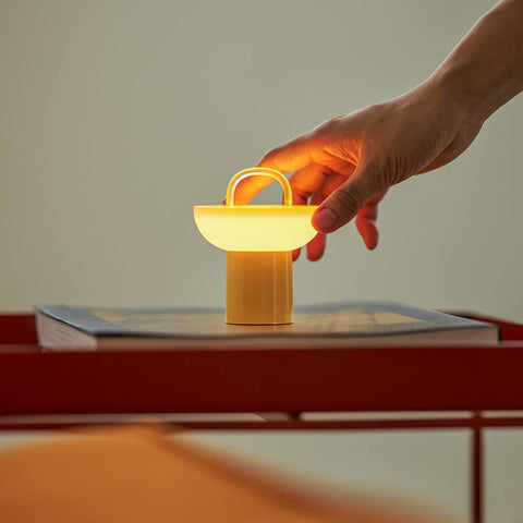 A model adjusting yellow Lumena Space S mood lamp on a table