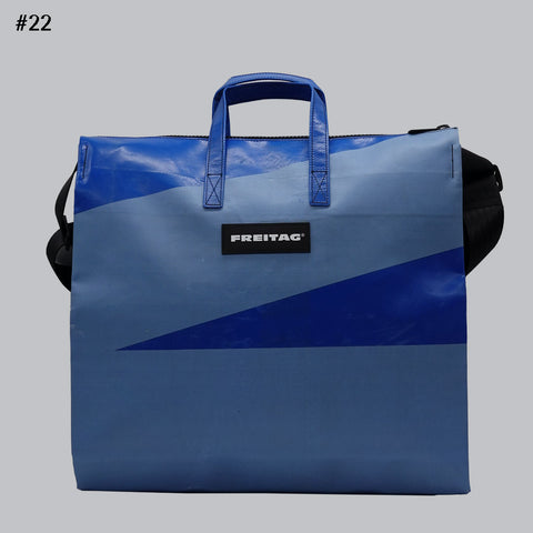 Front view of FREITAG F275 TILDA tote bag in blue and light blue, with blue handles and black shoulder strap.
