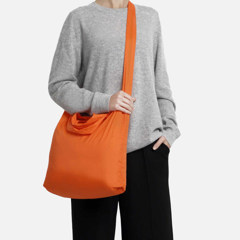 Model using the torii orange tetra tote bag in a crossbody form