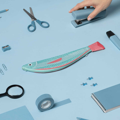 Don Fisher Verdin fish case with a sea of scissors, notepad, pencils, glasses, tape, stapler, small items which can be fit into the case