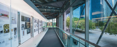 Museum gallery indoor hallway with exhibit panels and floor to ceiling windows overlooking Marina Bay