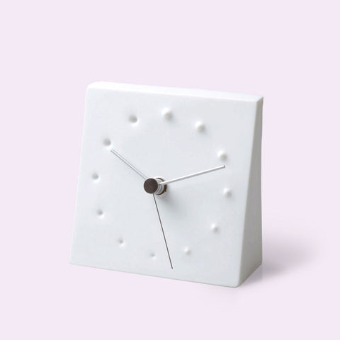 'Fireworks' minimalist square tabletop clock with a matte white face and hands, featuring small raised and recessed dot hour markers