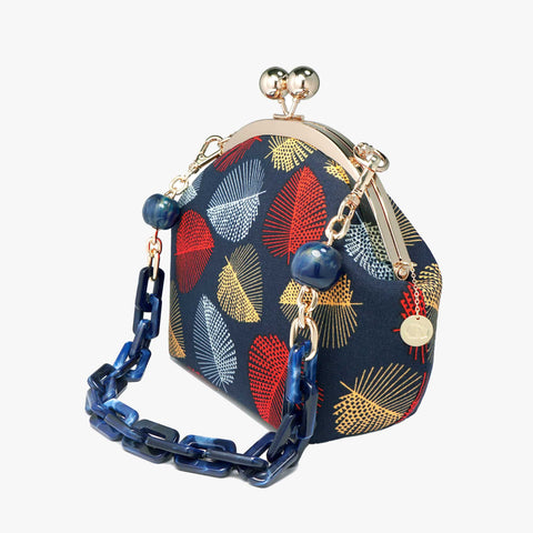 Cocoonese Arcylic Chain Handle Clasp Sling Bag-Fall (Red Black) with bold leaf motifs, gold clasp, and chunky blue chain for a striking, modern look