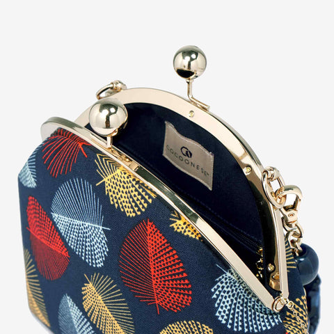 Close-up of Cocoonese Arcylic Chain Handle Clasp Sling Bag-Fall (Red Black), highlighting gold clasp, rich fabric, and vibrant leaf patterns
