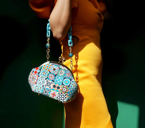 a model carries the Cocoonese Arcylic Chain Handle Clasp Sling Bag-Peranakan Tiles with ease, letting it drape stylishly for a bold, eye-catching look