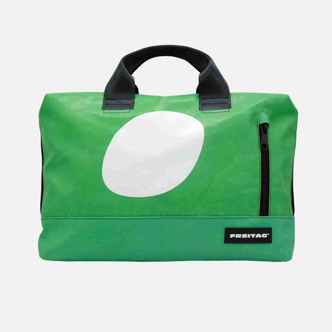 FREITAG F301 MOSS front image with a vibrant grass-green base dominates the bag, contrasted by a bold off-white oval accent, with black handles and zipper details adding sharp, modern contrast
