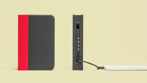 Two Lumio Lito book lamp of red and grey colour with one standing up right while the other is showing the charging cables for powerbank