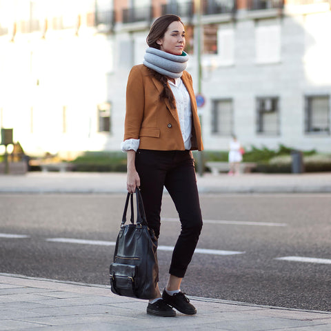 Model walks city streets wearing Ostrichpillow Light Versatile Pillow-Blue Reef, styled as a cozy neck cushion for comfort on the go