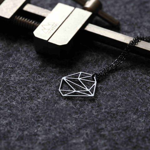 Moorigin Stainless Steel Pendant - Stone XS rests on textured fabric, its geometric lines contrasted by a rugged tool for a refined industrial feel