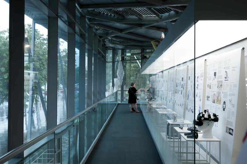 Person browsing museum exhibit in a steel and glass building with view of Marina bay outside