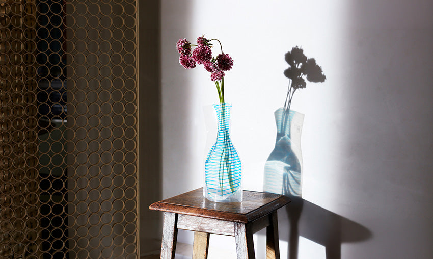 D-Bros Flower Vase in blue stripe pattern with pink flowers, on wooden stool.