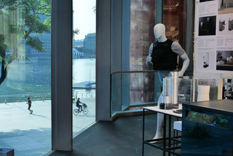 Mannequins displaying a concept design winner vest with a view of a waterfront and people doing outdoors activites