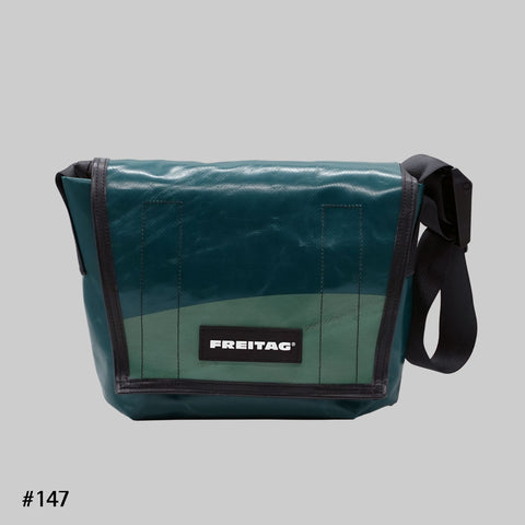 Front view of FREITAG F11 LASSIE messenger bag in dark green, with a lighter green flap and black strap