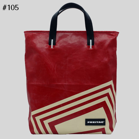 Front view of FREITAG F202 LELAND tote bag with black handles with red and off-white angular shapes.