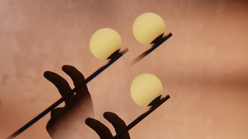 Close up of the Lumio Ovo lamp that shows the lit lamp in movement, with a dark hand silhouette against a warm peach-brown background.