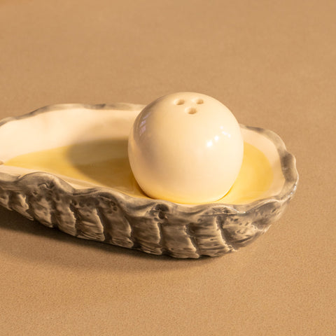 &Klevering white ceramic Oyster salt shaker in a textured ceramic holder on a beige background