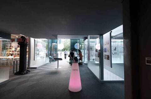 Interior of the gallery exhibit with lighted up cocktail tables and people gathering at the entrance along Marina bay
