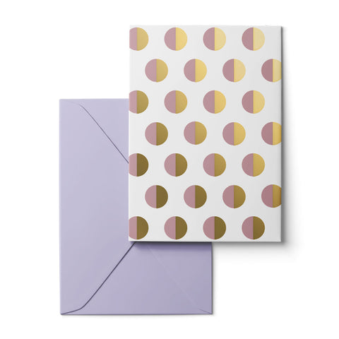 A white greeting card with a repeating pattern of half-gold and half-pink metallic circles, shown with a lavender envelope on a white background.