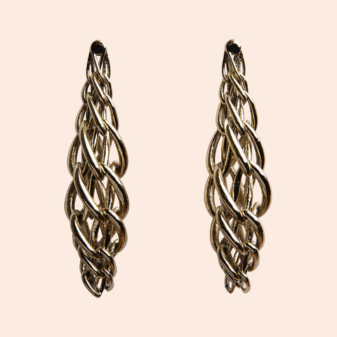 Pair of gold color geometrical patterns earrings on a beige background