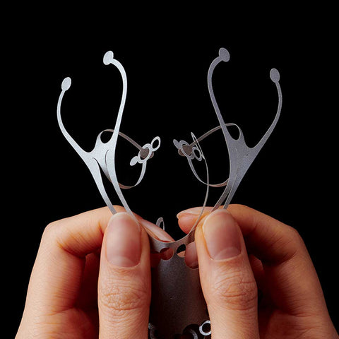 A pair of hands holding a paper cut-out pattern of the Wind Jelly Fish Hanging upright, called KURUKURU by Fukunaga Print Co., Ltd